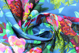 Swirled swatch New Flame fabric (blue fabric with large colourful floral and greenery allover in green, purple, pink, blue and yellow shades)