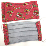 Front and back view of mask with white elastic ear loops (pink coral fabric mask with small tossed floral clusters with greenery in pink, red, yellow floral)