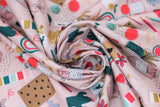 Swirled swatch supplies fabric (pale pink fabric with small tossed craft elements allover, journal, coloured pencils, paint swatches, glasses, pop poms, yarn, etc.)