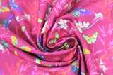 Swirled swatch Masako fabric (dark pink fabric with busy background including red and orange fibrous splatter shapes, grey branches with white flowers and pink leaves and butterflies tossed allover in multi-coloured shades)