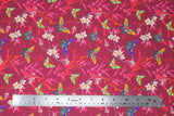 Flat swatch Masako fabric (dark pink fabric with busy background including red and orange fibrous splatter shapes, grey branches with white flowers and pink leaves and butterflies tossed allover in multi-coloured shades)