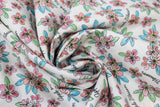 Swirled swatch Apple Blossom fabric (white fabric with tossed drawn style floral heads in pale red and pink with green and blue leaves and tossed "Apple Blossom" cursive writing in black)