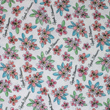 Square swatch Apple Blossom fabric (white fabric with tossed drawn style floral heads in pale red and pink with green and blue leaves and tossed "Apple Blossom" cursive writing in black)