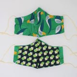 Front and back view of ninja style mask with off white elastic ear loops (green mask with white, blue and yellow style birds tossed and faint circular geometric pattern)