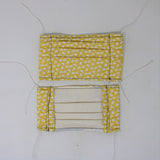 Front and back view of mask with white elastic ear loops (yellow mask with tiny tossed white bunnies allover)