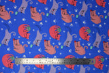 Flat swatch cats fabric (medium blue fabric with tossed white paw prints and tossed pale pink and purple illustrative style cats playing with yarn balls and mice)