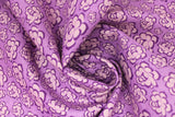Swirled swatch of peony printed fabric in purple (medium purple fabric with light purple cartoon peony heads tossed)