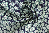 Swirled swatch of peony printed fabric in black (black fabric with light green cartoon peony heads tossed)