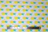Flat swatch of pineapple print fabric on white (tiled yellow and green pineapples with tossed tiny gold hearts)