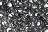 Swirled swatch of puppy heads printed fabric in black (black fabric with white doodled puppy heads tossed)