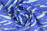 Swirled swatch of blue fabric in futuristic (dark blue fabric with white and light blue tossed polka dots and horizontal cloud lines in various blues, grey)