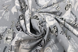 Swirled swatch of assorted Friday the 13th pattern on grey (grey fabric with multi emblems tossed in black and white. Crossing checkered flags, 13 badges, "Port Dover Motorcycle Rally" text, wheels, etc.)