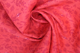 Swirled swatch of sea life fabric in red aquatic plants (bright cherry red fabric with tossed dark red sea plants outlines and white bubbles)