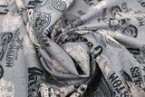 Swirled swatch of assorted Canadian custom motorcycles fabric in grey (grey fabric with tossed logo and text related to Canadian custom motorcycles "Custom" text, etc. in white, black)