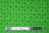 Flat swatch Clover Swirls fabric (green fabric with tossed green shamrocks outlined with gold sparkles and tossed thin black swirls)
