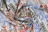 Swirled swatch farmhouse text fabric (white barnboard style background with tossed red, blue, and black text allover "Strawberries" "Farmhouse" etc. and small graphics related to farm)