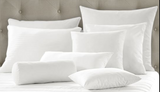 Assorted pillow forms arranged on a grey bed frame with white sheets