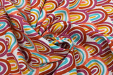 Swirled swatch Primary Rainbows fabric (white fabric with tightly packed abstract drawn style rainbows in pale shades: yellow, magenta, peach/coral, burnt orange)
