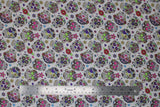 Flat swatch small white sugar skulls fabric (white fabric with small tossed white and multi-coloured sugar skulls allover with tossed colourful floral)