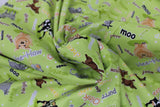 Swirled swatch World of Susybee printed fabric in Farm Animals & Words on Green