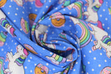 Swirled swatch blue unicorns & donuts fabric (medium blue fabric with small white polka dots and tossed cartoon white unicorns with rainbow main and pink bangs/tails, tossed cartoon rainbows with smiling clouds, tossed brown donuts half dipped in pink with sprinkles, tossed stars)