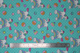 Flat swatch green unicorns & donuts fabric (teal green fabric with small white polka dots and tossed cartoon white unicorns with rainbow main and pink bangs/tails, tossed cartoon rainbows with smiling clouds, tossed brown donuts half dipped in pink with sprinkles, tossed stars)
