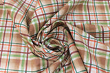 Swirled swatch light brown plaid fabric (light brown plaid squares with dark brown, red, and green plaid lines)