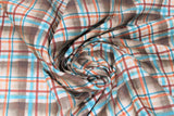 Swirled swatch dark brown plaid fabric (dark brown plaid squares with maroon, orange, and blue plaid lines)