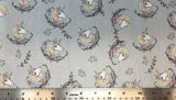 Flat swatch cartoon unicorn head printed fabric in grey (grey fabric with tossed cartoon white/purple/yellow pastel unicorn heads with pink and purple floral swoopy decoration)