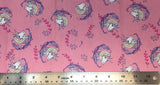 Flat swatch cartoon unicorn head printed fabric in pink (pink fabric with tossed cartoon white/purple/yellow pastel unicorn heads with pink and purple floral swoopy decoration)