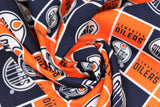 Swirled swatch licensed NHL fabric in Edmonton Oilers (quilt squares pattern with orange and navy backgrounds with logo, orange background with team text)
