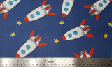 Flat swatch cartoon rocketships fabric in navy (dark blue fabric with tossed cartoon rocket ships in white/red/grey/blue and tossed yellow stars)