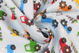 Swirled swatch tractors fabric (pale light blue fabric with red, orange, green and blue cartoon tractors allover with small white cloud exhaust and grey picket fence sections)