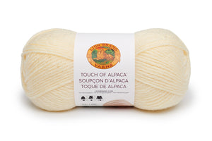 A ball of Lion Brand Touch of Alpaca yarn in cream shade on white background