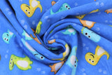 Swirled swatch cartoon dino fabric (medium blue fabric with tossed cartoon dinosaurs in blue, green, yellow, orange with smiling faces, tossed light blue dino tracks)