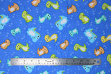 Flat swatch cartoon dino fabric (medium blue fabric with tossed cartoon dinosaurs in blue, green, yellow, orange with smiling faces, tossed light blue dino tracks)