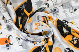 Swirled swatch Halloween town fabric (white fabric with grey road look lines allover and Halloween themed town graphics allover: black castle look buildings, tombstones, ghosts, skeletons, etc. all in a white, grey, black, orange colourway)