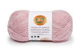 A ball of Lion Brand Touch of Alpaca yarn in blush shade on white background (pale rose pink)