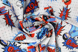 Swirled swatch of cartoon superhero print pattern in blue (white fabric with grey polka dots, cartoon superhero characters in blue, black and red colourway with comic book style words and logos "POW!" etc)