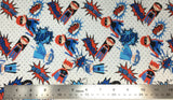 Flat swatch of cartoon superhero kids print pattern in blue (white fabric with faint grey polka dots, tossed blue/red/black super hero kids with capes and cartoon words text "Crash" etc.)