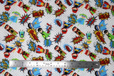 Flat swatch of cartoon superhero print pattern in primary colours (white fabric with grey polka dots, cartoon superhero characters in blue, green, yellow and red colourway with comic book style words and logos "POW!" etc)