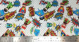 Flat swatch of cartoon superhero kids print pattern in primary colours (white fabric with faint grey polka dots, tossed blue/red/yellow/green super hero kids with capes and cartoon words text "Crash" etc.)