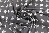 Swirled swatch skull printed fabric in small white skull and crossbones on black