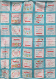 Full panel swatch - Grid Panel (44" x 24") (light turquoise rectangular panel with 35 white/off white squares within depicting crafting images and graphics: sewing machines, scissors, etc. red colourway)