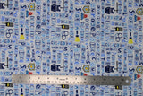 Flat swatch Words fabric (white fabric with police related text allover in blue with square outlines: "Protect" "Teamwork" etc. with scattered cartoon style police related emblems: cuffs, vest, flashlight, etc.)