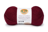 A ball of Lion Brand Touch of Alpaca yarn in crimson shade on white background (burgundy)