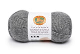 A ball of Lion Brand Touch of Alpaca yarn in oxford grey shade on white background
