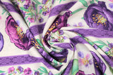 Swirled swatch violette fabric in striped violettes (white fabric with purple stripes separating purple floral designs, large floral heads and greenery, small floral with lots of greenery)