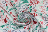Swirled swatch Words fabric (white fabric with horizontal and vertical cursive christmas themed words allover in red, green and navy: "Ho Ho Ho" "Miracle" "North pole" etc. with small red and green emblems: snowflakes and holly, trees, etc.)