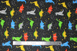 Flat swatch space dinos fabric (black fabric with tossed grey and yellow and white stars and constellations with green, yellow, blue, orange, grey cartoon dinosaurs allover with astronaut helmets)